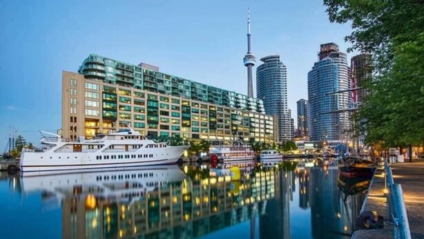 A waterfront hotel with a large building, a prominent tower, and a reflection in the water.