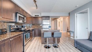 Una cocina moderna con armarios de madera oscura, electrodomésticos de acero inoxidable, encimeras de granito y una zona de bar con taburetes.