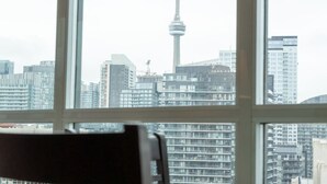 Vista a través de una ventana de un paisaje urbano con edificios altos y una torre destacada.