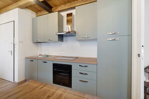 Una cucina moderna con mobili grigi, una cappa in acciaio inossidabile e un forno a incasso.