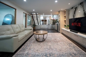 Relax in the spacious living room with comfortable seating and a 65" Smart TV. - Modern 3BR Basement Retreat w/ Workspace & Parking (Toronto)