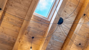 Een houten plafond met zichtbare balken, een dakraam en hanglampen.