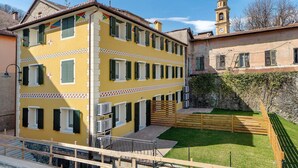 A yellow building with multiple windows and a small courtyard. - Studio Apartment with Garden (Rossiglione)
