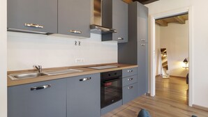 Une cuisine moderne avec des meubles gris, des appareils en acier inoxydable et un plan de travail en bois.