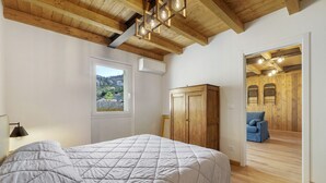 Une chambre à coucher avec un lit, une armoire, une fenêtre et une vue sur un canapé bleu situé dans la pièce adjacente.