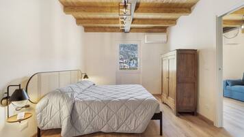 Una camera da letto con un letto, un armadio in legno, una finestra vista e una porta che conduce in un'altra stanza.