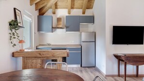 Une cuisine moderne avec des poutres en bois, un coin repas et un téléviseur à écran plat.