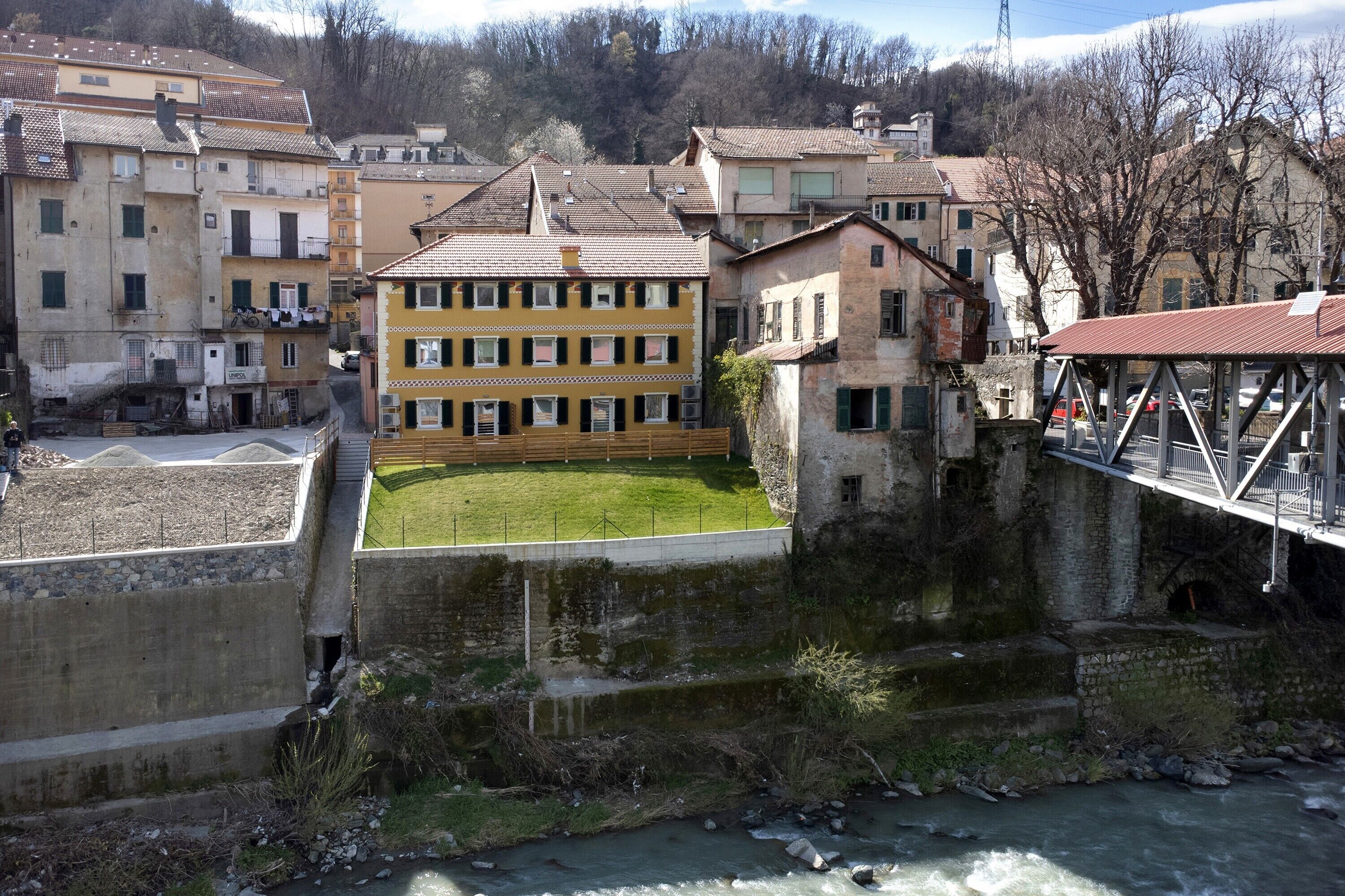 Vista do rio de uma cidade com edifícios históricos, uma ponte e uma área gramada.