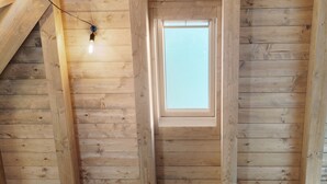 Un intérieur en bois agrémenté d’une lucarne, de poutres en bois et d’un luminaire.