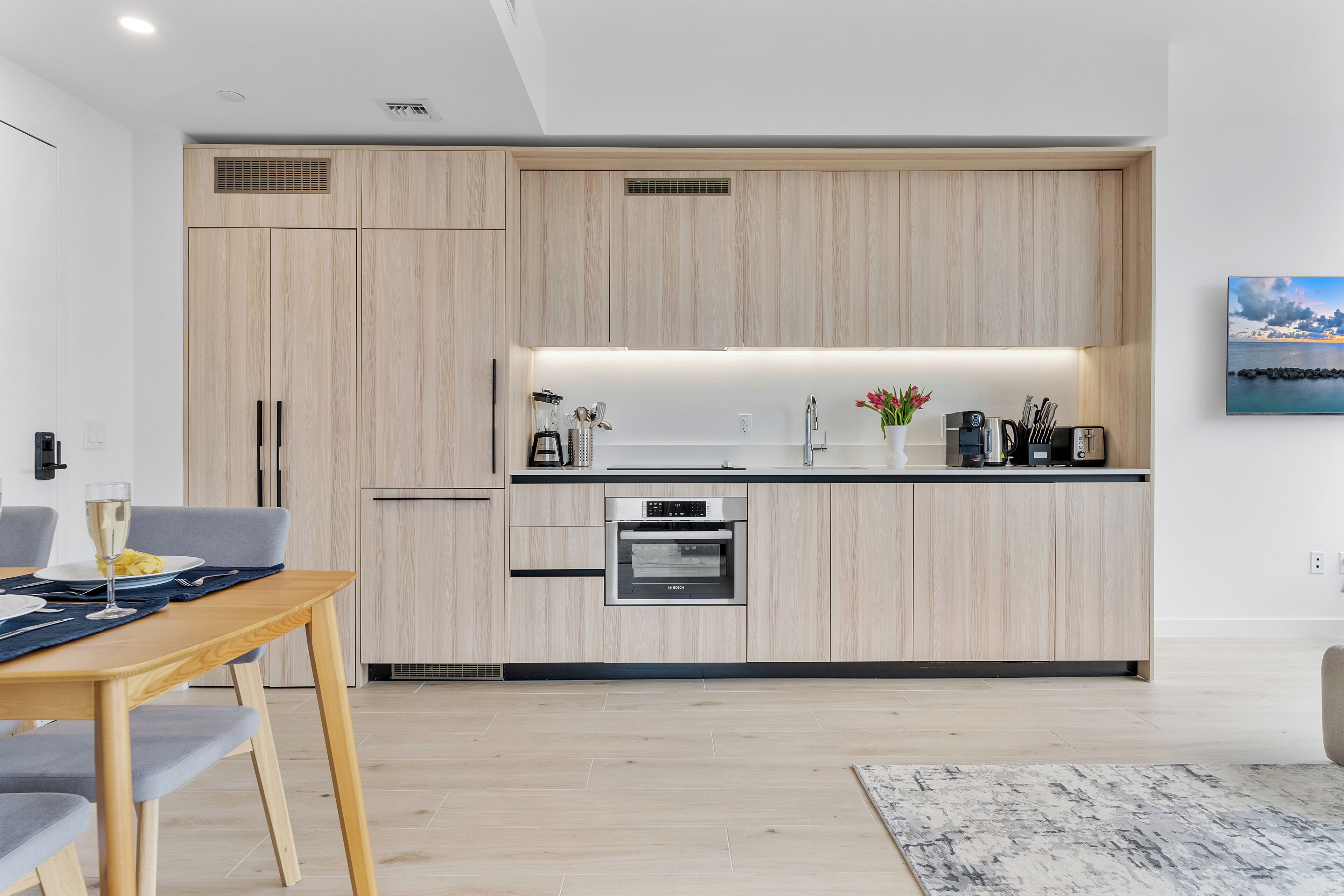 Una cucina moderna con mobili in legno, forno integrato e zona pranzo con tavolo e sedie.