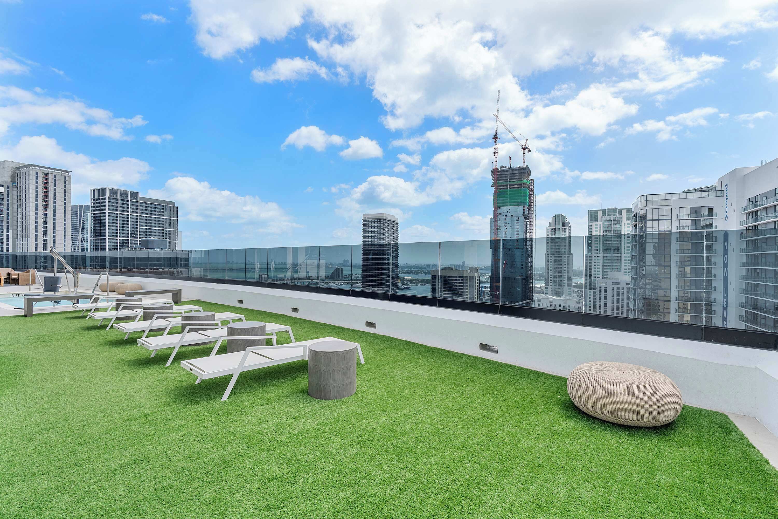 Een terras op het dak met kunstgras, lounge stoelen en een moderne zithoek.