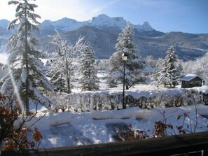 Un paysage de montagne enneigé, avec des arbres et un chalet.