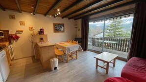 A cozy room with a dining area, a small kitchen, and a balcony with a mountain view. - Apartment near the ski resort in Barcelonnette (Barcelonnette)