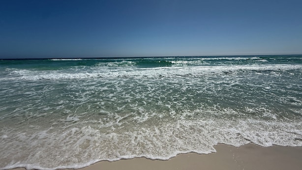 Una playa con olas lamiendo suavemente la orilla.