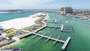 Una marina costera con playa, un puente y un hotel al fondo.