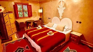 Un dormitorio con cama, mesitas de noche, un escritorio y una silla.