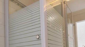 Une salle de bain avec une douche à parois de verre, un lavabo blanc et un miroir.