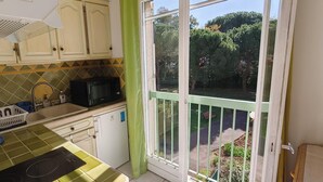Cozinha com micro-ondas, pia e vista para um jardim através de uma porta de correr.