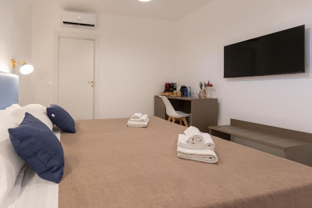 Un dormitorio con cama, escritorio, silla, televisor y puerta.