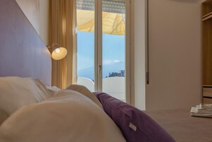 A bedroom with a bed, a nightstand, a lamp, and a view through a door.