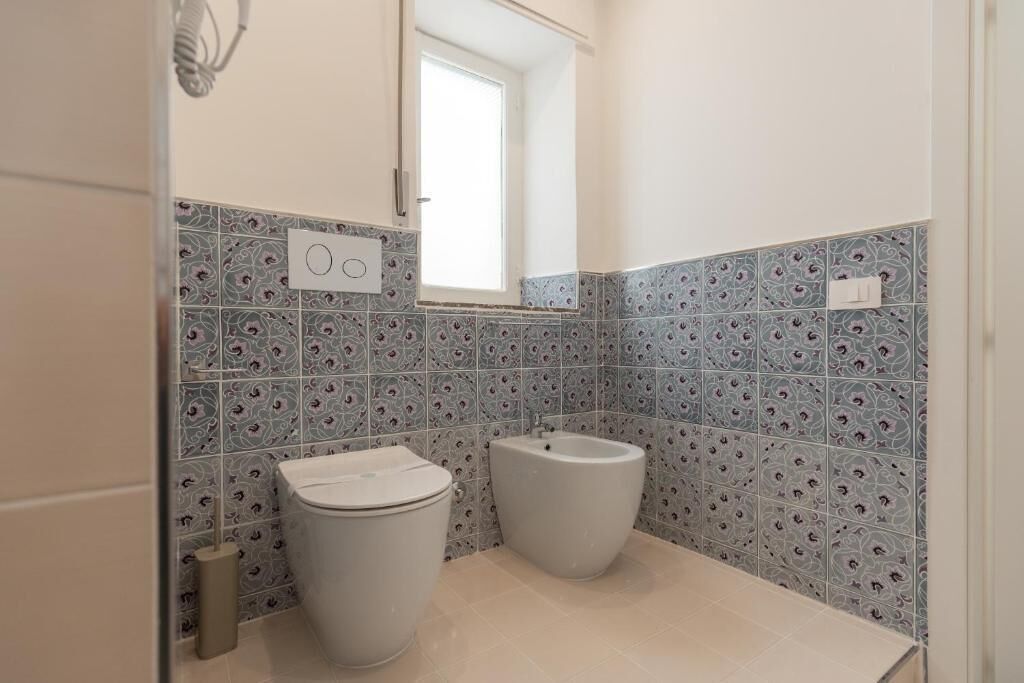 Une salle de bain équipée de toilettes, d’un bidet et de carreaux décorés.