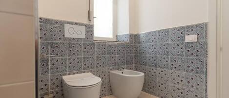 Une salle de bain équipée de toilettes, d’un bidet et de carreaux décorés.