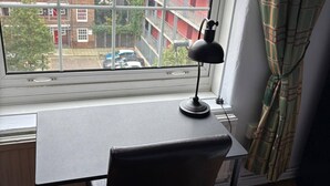 Une pièce comprenant un bureau, une chaise et une fenêtre donnant sur un paysage urbain.