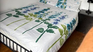Une chambre à coucher avec un lit, une table de chevet, une lampe et des œuvres d’art murales.