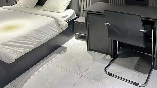 A modern bedroom with a bed, bedside table, and a desk with a chair.