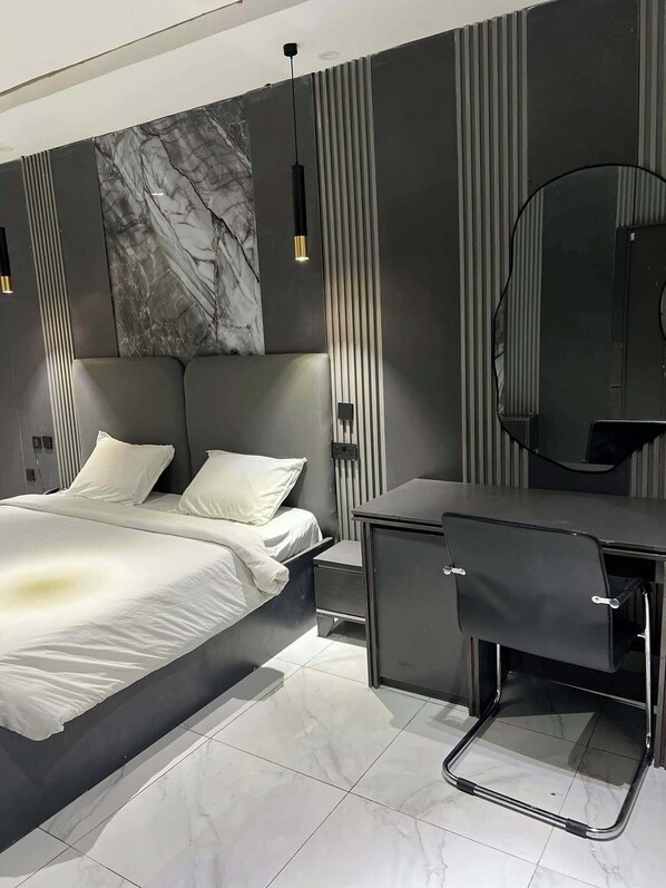 A modern bedroom with a bed, bedside table, and a desk with a chair.