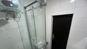 A bathroom with a glass shower enclosure, a toilet, and a bathtub.