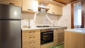 Een moderne keuken met een koelkast, fornuis, oven en houten kastjes.