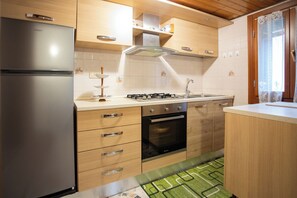 A modern kitchen with a refrigerator, stove, oven, and wooden cabinets. - Dimora Papi -apeliving- Pellestrina (VE) (Venezia)
