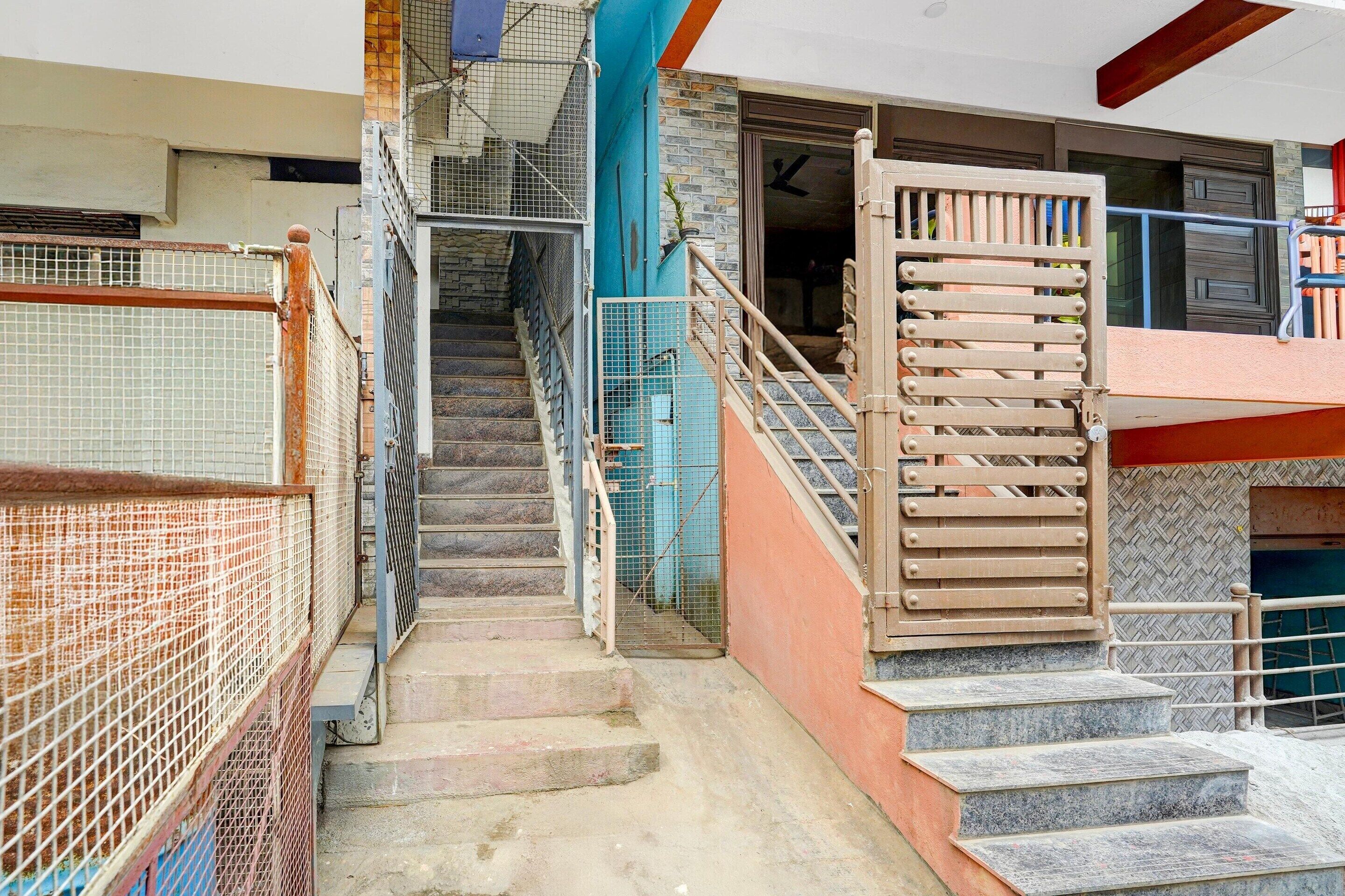 A staircase leading to a building entrance with a metal gate and a wooden handrail.