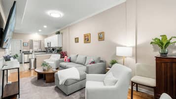 Una sala de estar moderna con un sofá gris, una mesa de centro y un televisor montado en la pared.