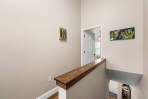 A staircase with a wooden handrail, a white door at the top, and two paintings on the walls.