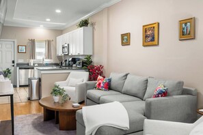 A modern living room with a grey sofa, a coffee table, and a kitchen in the background.