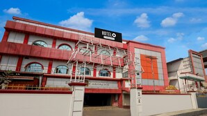Un hotel con un cartello evidente, un ingresso con cancello e una facciata rosso e bianco.