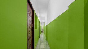 Un corridoio stretto con pareti verdi e pavimento piastrellato, che conduce a una porta con pomello decorativo.