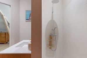 Un baño moderno con ducha, lavamanos y un armario de madera.