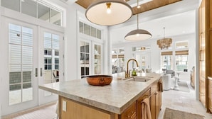 A spacious kitchen with a large island, pendant lighting, and a view to the living area. - Ciao Bella 721 COA (Port Aransas)