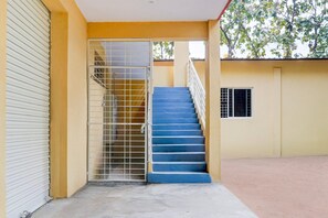 A building with a closed shutter door, a metal gate, and a blue staircase leading to an upper level.