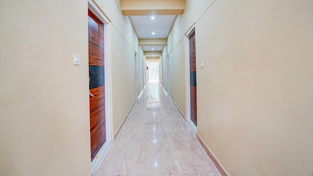 A long, narrow hallway with wooden doors on both sides, a marble floor, and a ceiling with recessed lighting. - Hotel O Bidadi Railway Junction (Ramanagara)