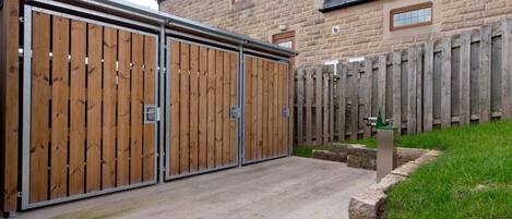A gated driveway leading to a stone building with a wooden fence.