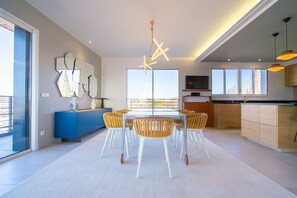 A modern kitchen with a large window, a dining area with a table and chairs, and a blue cabinet. - Penthouse 170m2 with Jacuzzi (La Teste-de-Buch)