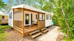 A mobile home with a porch, wooden steps, and a fenced area. - Mobil-home tout confort Camping de l’Escale C43 terrasse, piscine & plages (Agde)