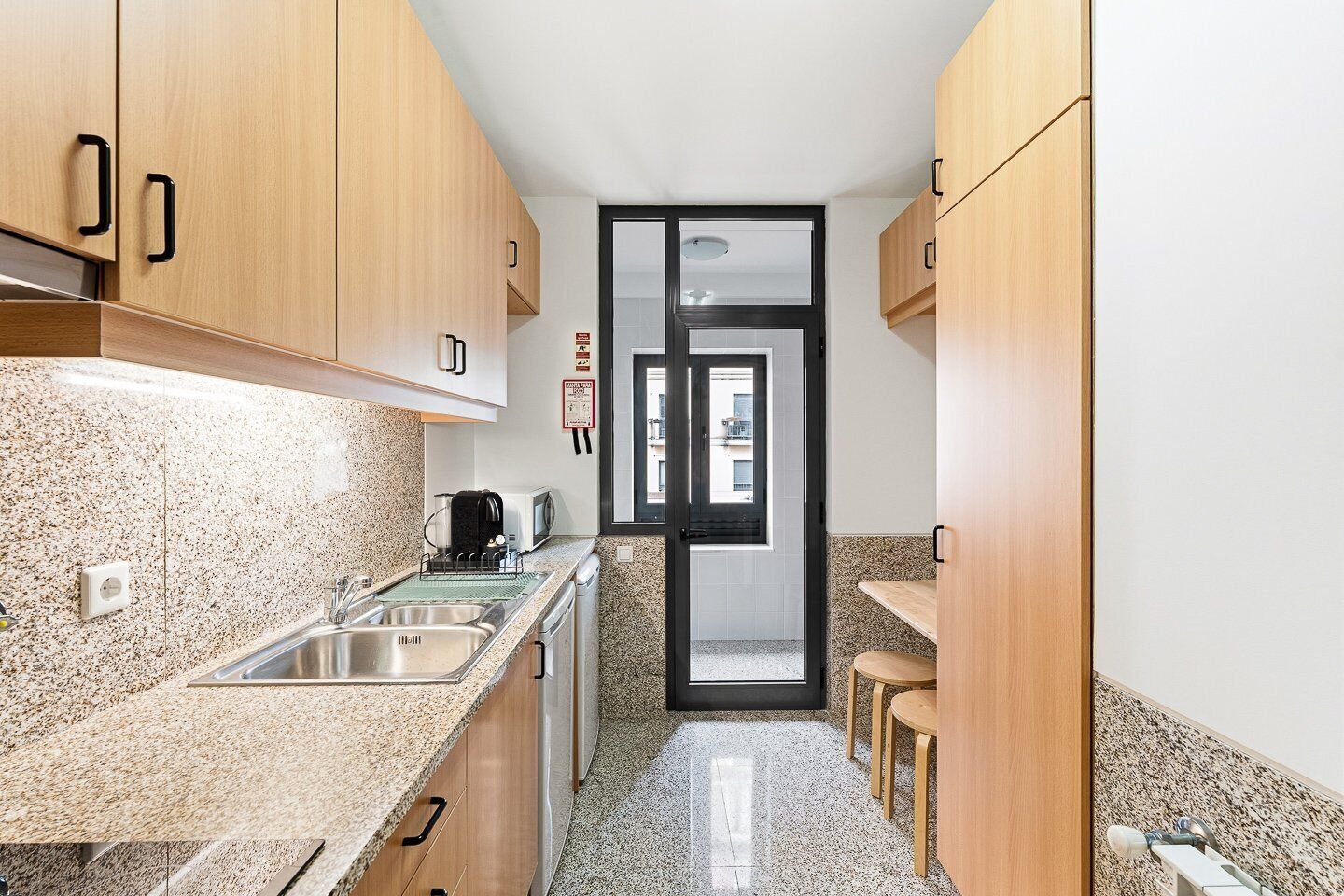 A kitchen with granite countertops, wooden cabinets, a sink, and a toaster.