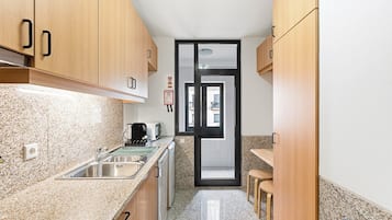 A kitchen with granite countertops, wooden cabinets, a sink, and a toaster.