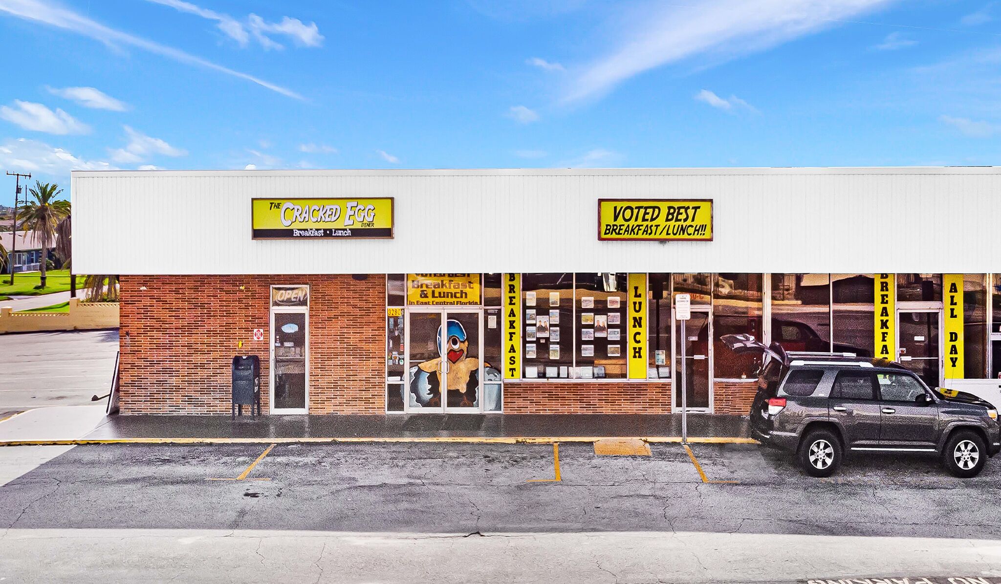 A building with a sign for 'The Cracked Egg' and another sign stating 'Voted Best Breakfast/Lunch'.