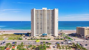 Ein Hochhaus-Hotel mit mehreren Etagen, Blick auf den Strand und einem Parkplatz mit Autos.